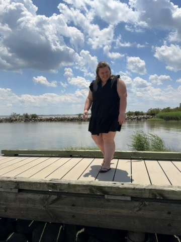 Emily, founder of Good for Your Cup Coffee Co., smiling on a waterfront dock under a sunny sky